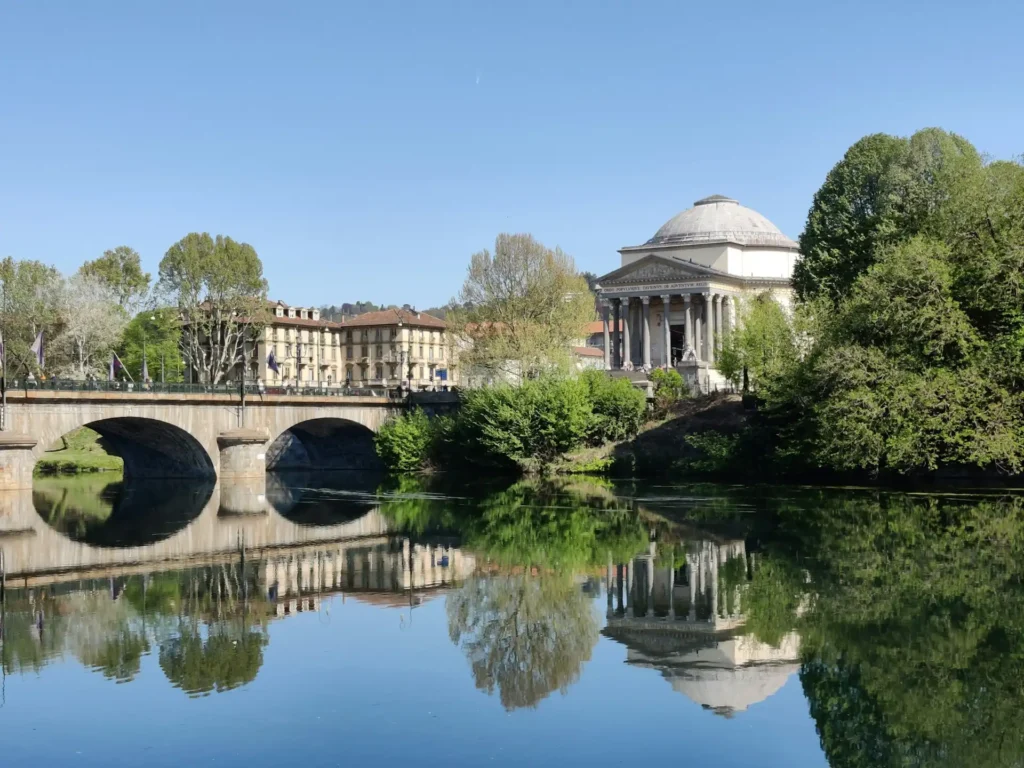 Nell'immagine, una veduta di Torino lungo il Po, con una grande area verde ed un ponte