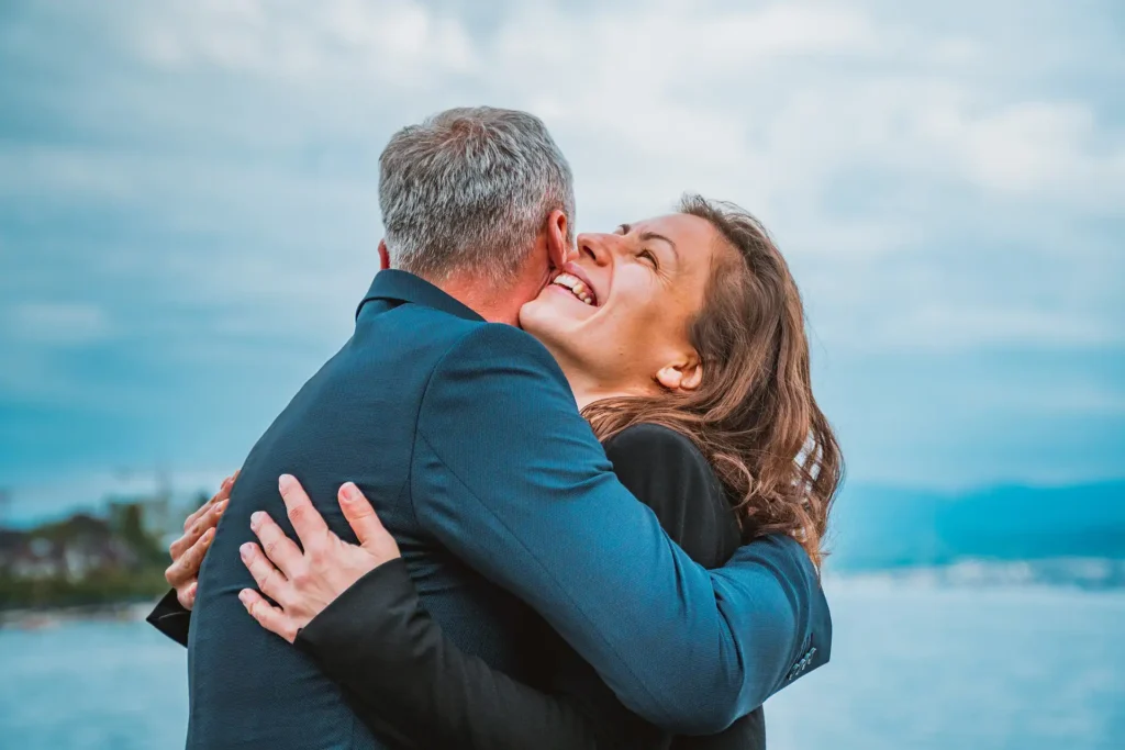 In the image, a close-up of a middle-aged couple embracing, and in the background, you can see the sea